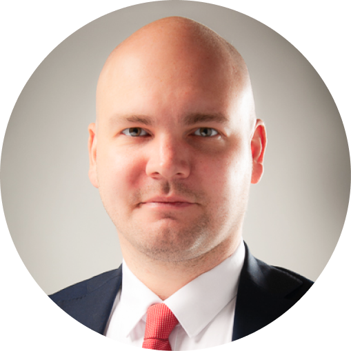 Man wearing a suit with a red tie against a plain background