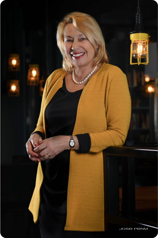 Woman wearing a yellow cardigan in a dimly lit room with hanging lights.