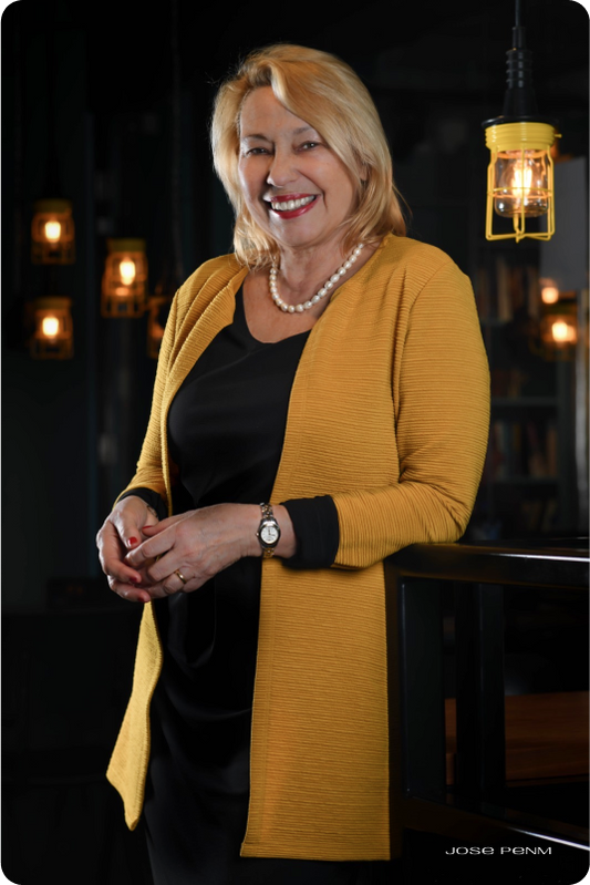 Woman wearing a yellow cardigan in a dimly lit room with hanging lights.